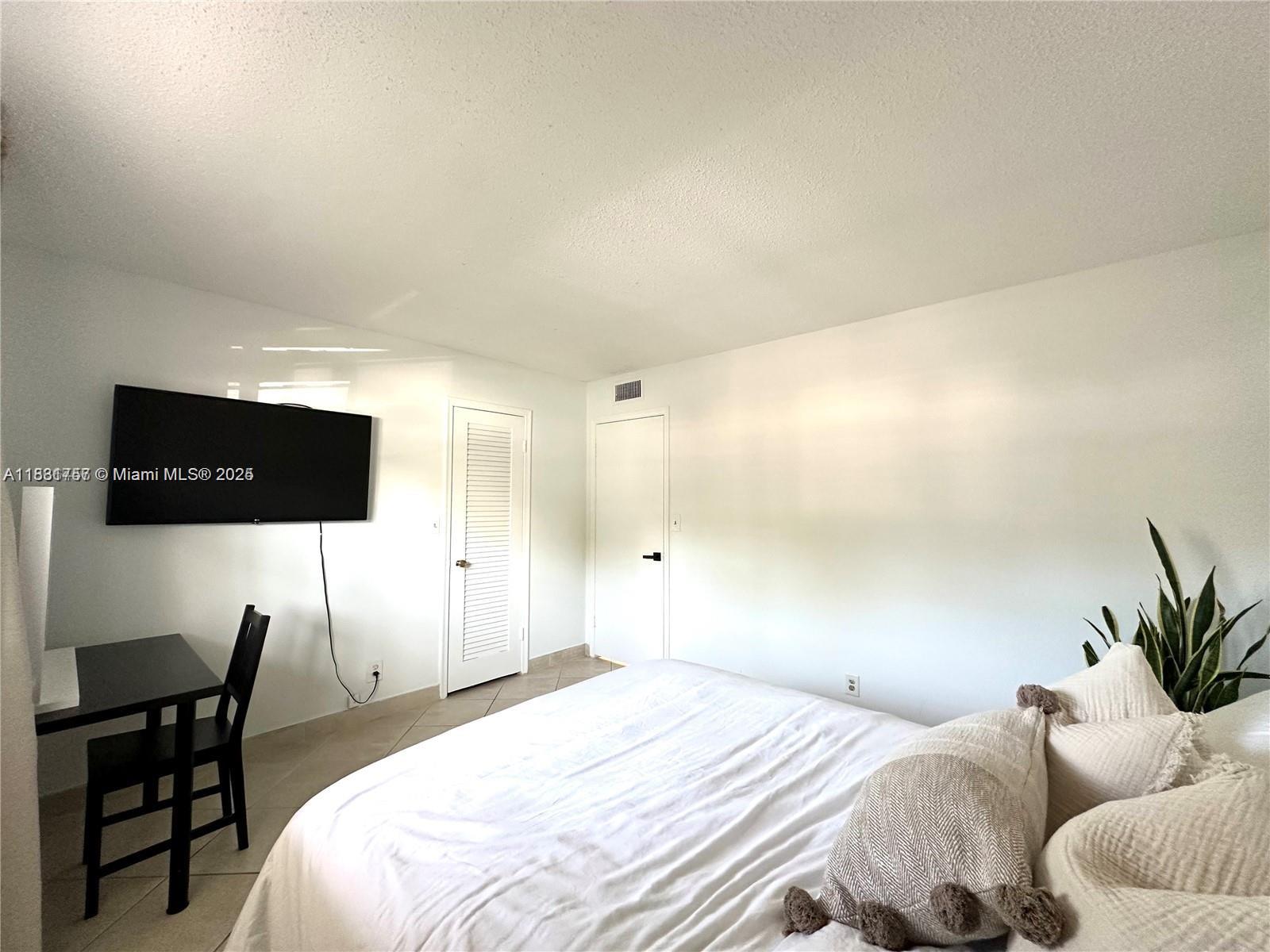 620 Northeast 12th Avenue, Unit 102 Hallandale Beach, FL 33009 - Photo 19 of 23 a bedroom with a bed and a potted plant