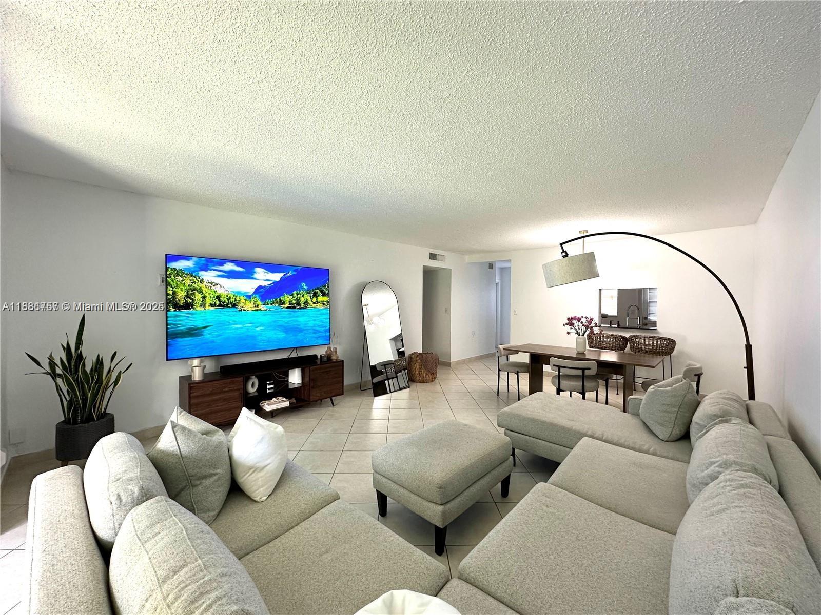 620 Northeast 12th Avenue, Unit 102 Hallandale Beach, FL 33009 - Photo 4 of 23 a living room with furniture a flat screen tv and a fireplace