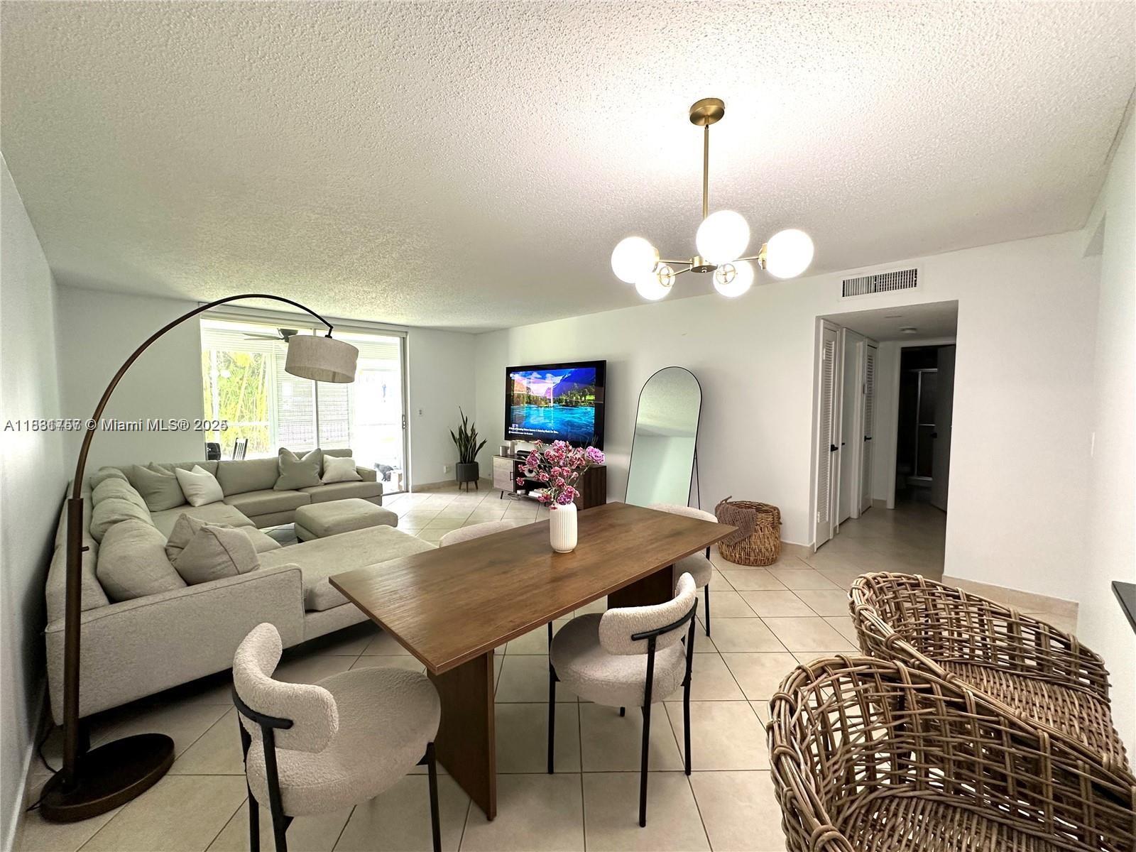 620 Northeast 12th Avenue, Unit 102 Hallandale Beach, FL 33009 - Photo 5 of 23 a living room with furniture a mirror and a chandelier