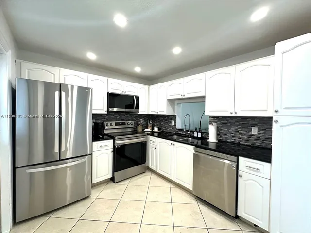 a kitchen with stainless steel appliances granite countertop a refrigerator stove a sink and a microwave