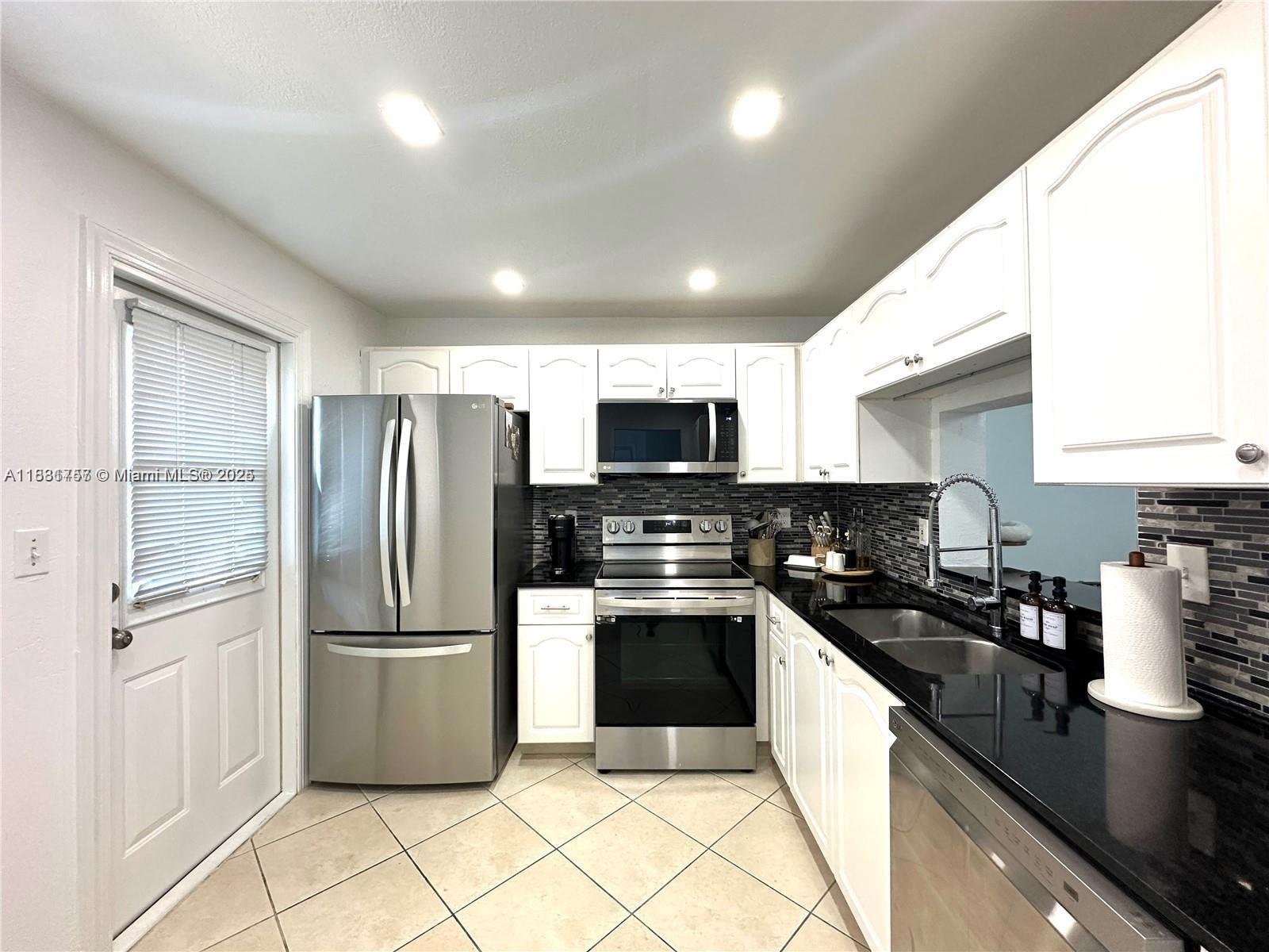 620 Northeast 12th Avenue, Unit 102 Hallandale Beach, FL 33009 - Photo 8 of 23 a kitchen with granite countertop a refrigerator and a sink