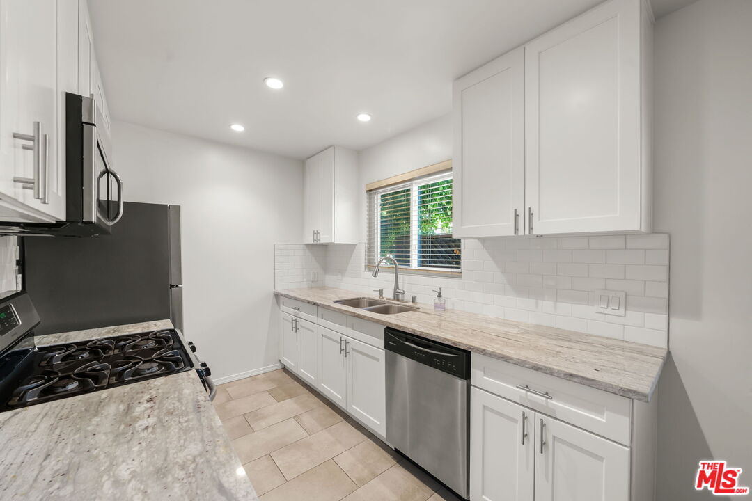 1517 Harvard Street, Unit 3 Santa Monica, CA 90404 - Photo 12 of 20 a kitchen with granite countertop a sink stove and cabinets