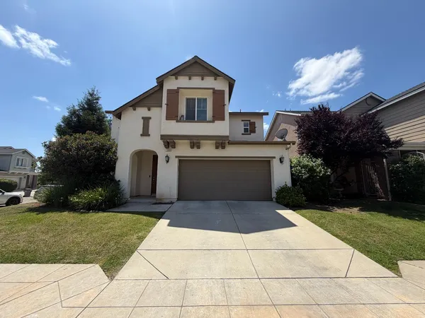 a front view of a house with a yard and trees
