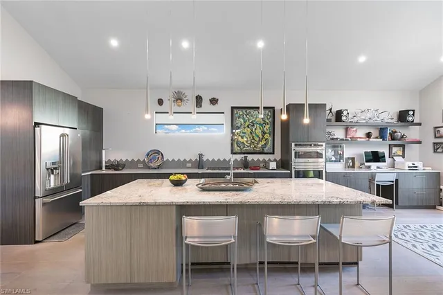 a kitchen with stainless steel appliances granite countertop a sink a stove a refrigerator cabinets and chairs