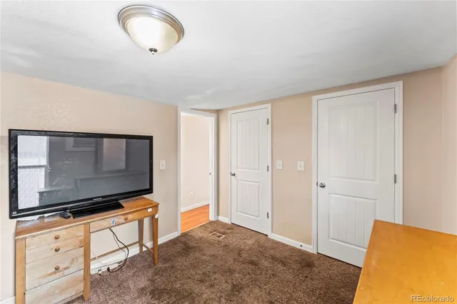a view of a hallway with wooden floor and a bathroom