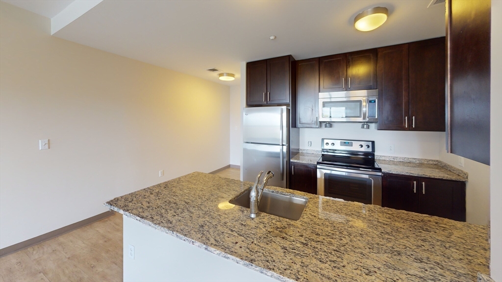 225 Centre Street, Unit 621 Boston, MA 02119 - Photo 2 of 9 a kitchen with granite countertop a refrigerator and a sink