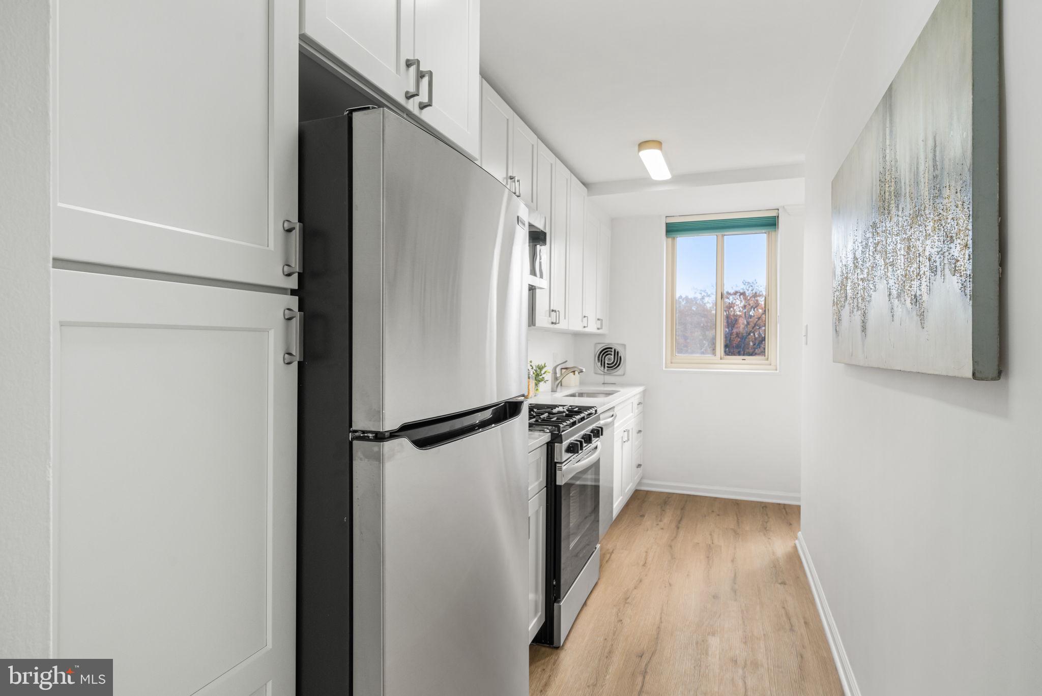 4000 Tunlaw Road Northwest, Unit 811 Washington, DC 20007 - Photo 9 of 51 a kitchen with granite countertop a refrigerator a sink and white cabinets
