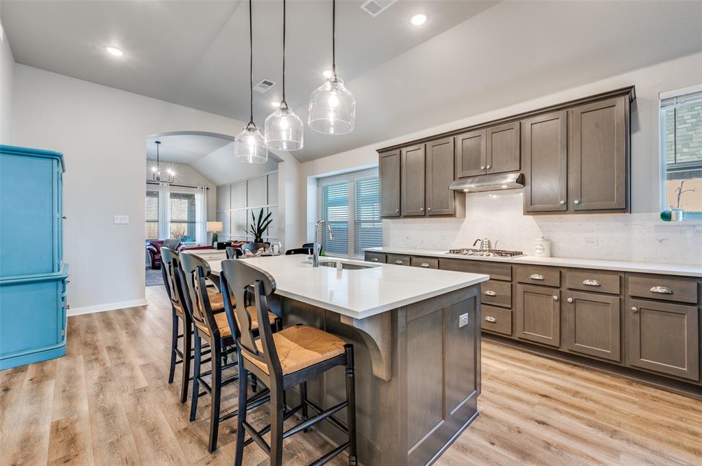 3513 Dusty Miller Road Aubrey, TX 76227 - Photo 11 of 25 a kitchen with stainless steel appliances granite countertop a kitchen island a stove a table and chairs in it