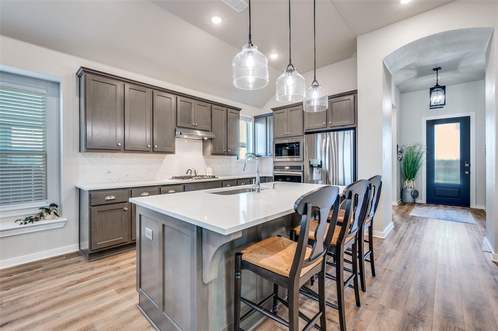 3513 Dusty Miller Road Aubrey, TX 76227 - Photo 6 of 25 a kitchen with stainless steel appliances a dining table chairs stove refrigerator and cabinets