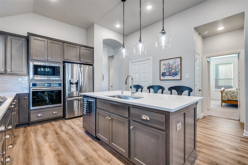 3513 Dusty Miller Road Aubrey, TX 76227 - Photo 9 of 25 a kitchen with stainless steel appliances granite countertop a sink a stove and a refrigerator