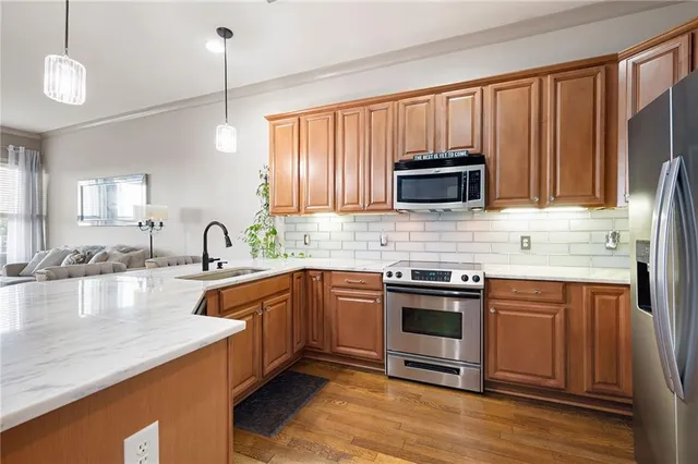 a kitchen with stainless steel appliances granite countertop a stove a sink dishwasher and a microwave oven with wooden cabinets