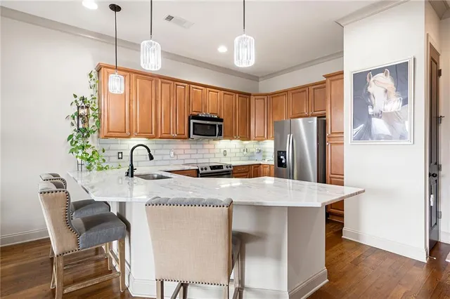 a kitchen with stainless steel appliances granite countertop a refrigerator a sink a stove a dining table and chairs