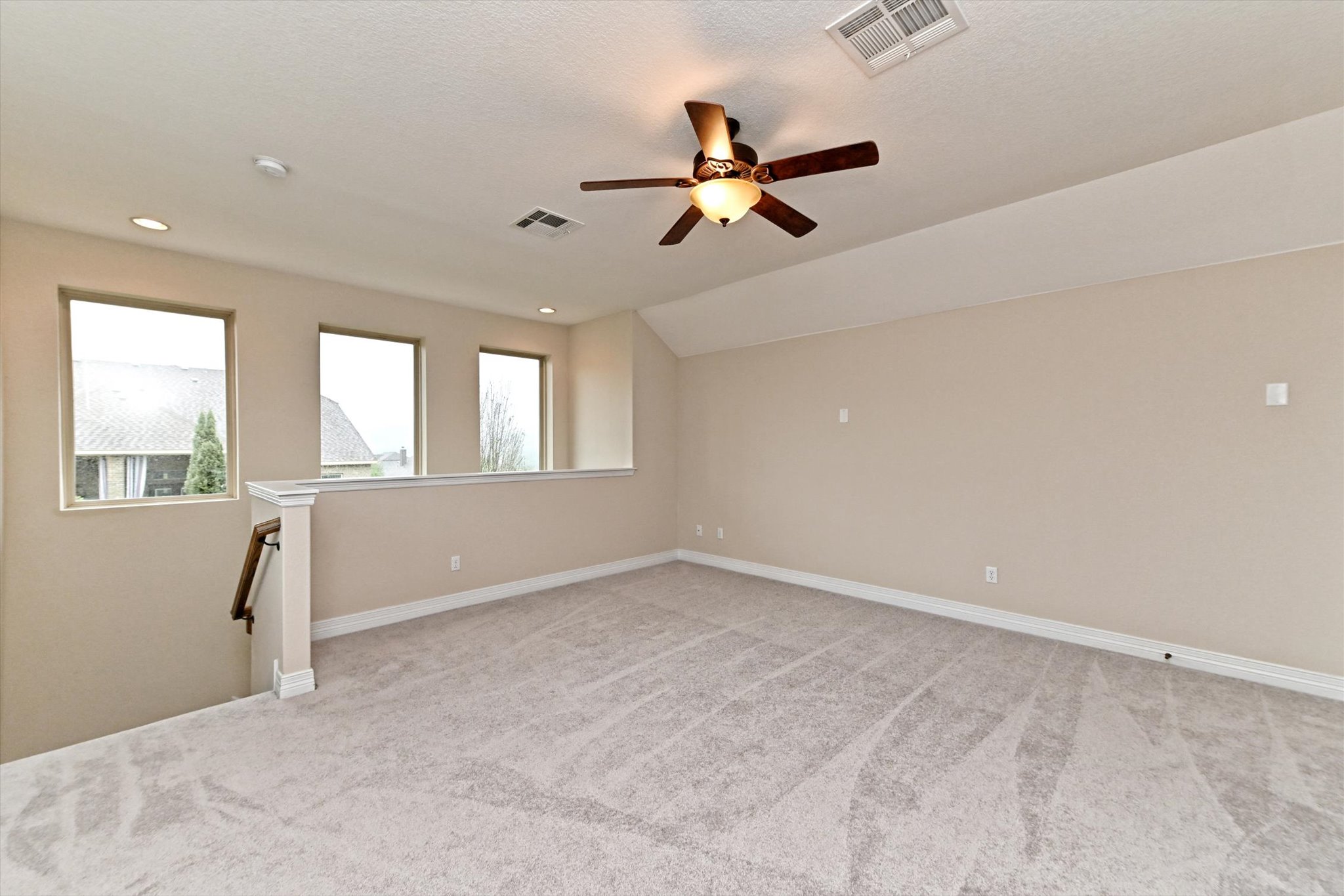18500 Rio Chama Lane Austin, TX 78738 - Photo 16 of 28 Spacious room featuring light-colored carpeting, three windows, and a ceiling fan with integrated lighting
