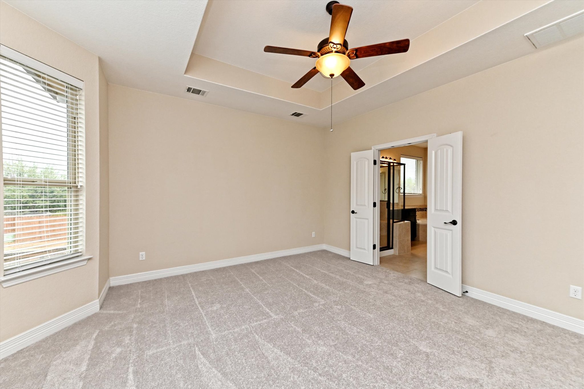 18500 Rio Chama Lane Austin, TX 78738 - Photo 18 of 28 Spacious room featuring light-colored walls, carpeted flooring, a tray ceiling with a ceiling fan, and a window with blinds