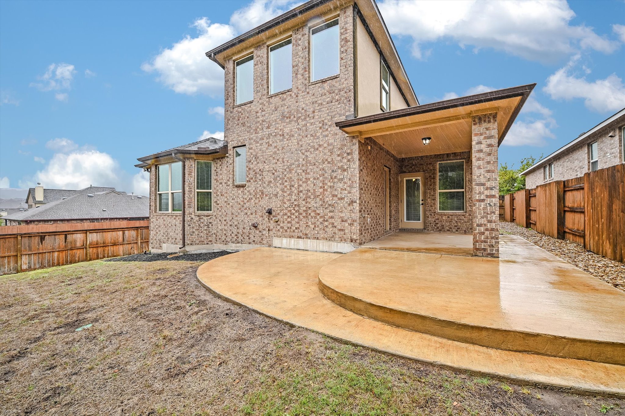 18500 Rio Chama Lane Austin, TX 78738 - Photo 28 of 28 The property features a brick exterior, an outdoor covered patio with a ceiling light fixture, and a concrete patio area