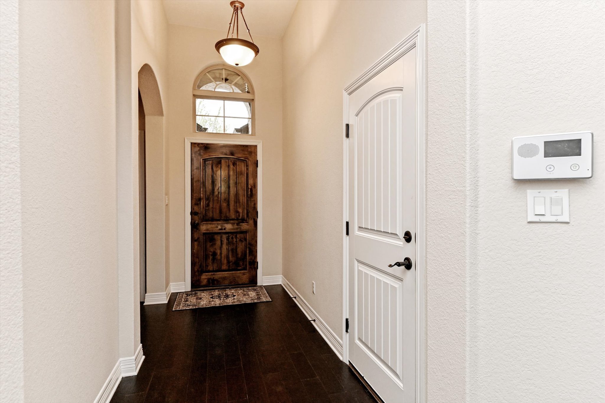 18500 Rio Chama Lane Austin, TX 78738 - Photo 3 of 28 The property features a entryway with dark hardwood floors, a rustic wooden door, and an arched transom window