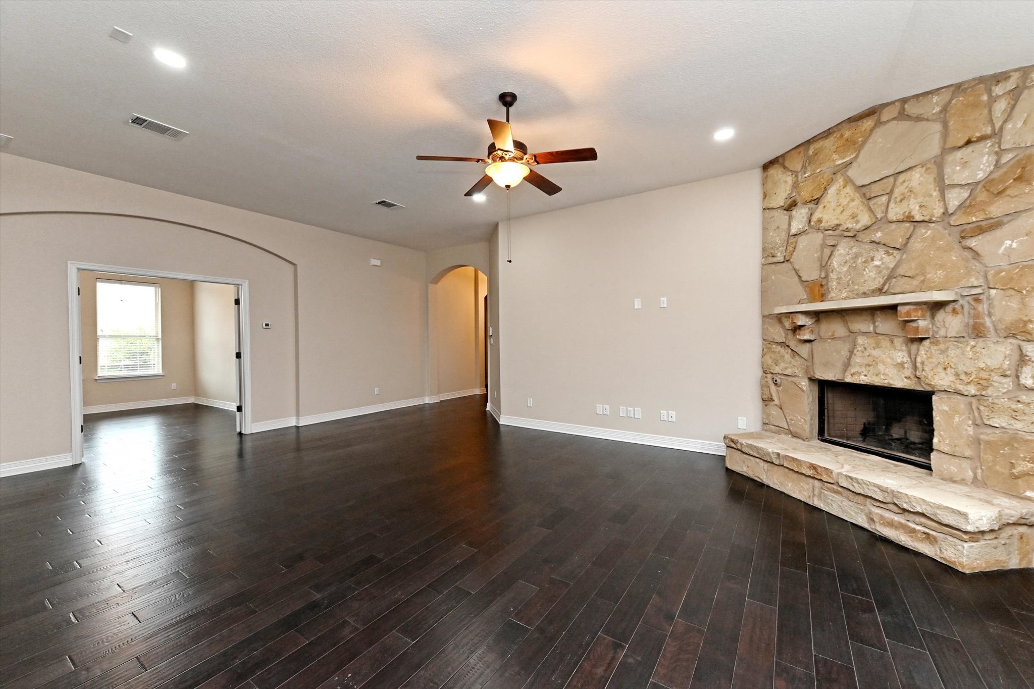 18500 Rio Chama Lane Austin, TX 78738 - Photo 5 of 28 This expansive living area features dark wood flooring, a stone fireplace with a hearth, and recessed lighting