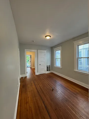 a view of empty room with window and wooden floor