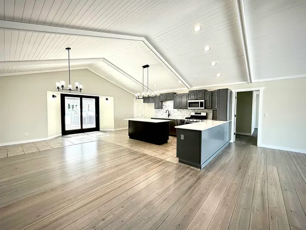 a large kitchen with stainless steel appliances kitchen island granite countertop a stove and a wooden floors