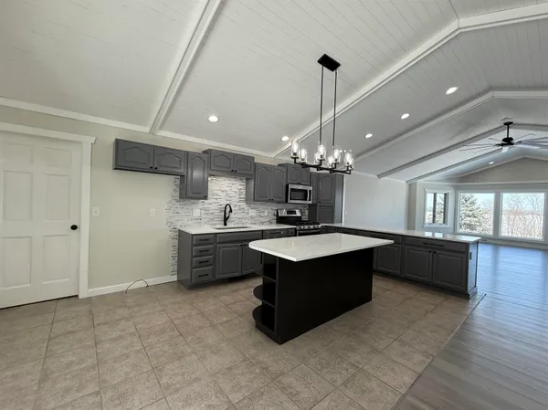 a large kitchen with kitchen island a island a stove a sink dishwasher and a oven with wooden floor