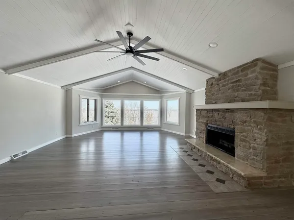 a view of an empty room with wooden floor fireplace and a window