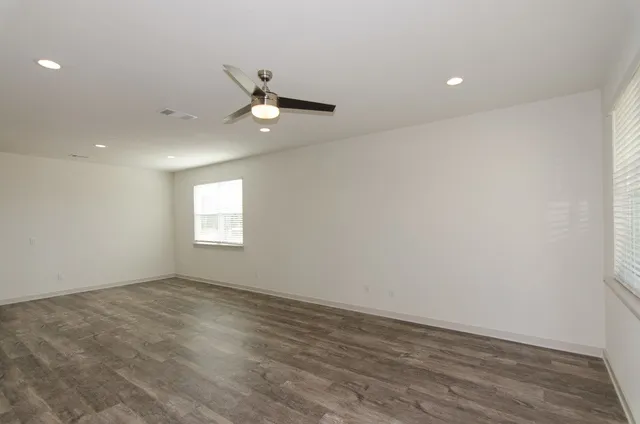 an empty room with wooden floor and windows