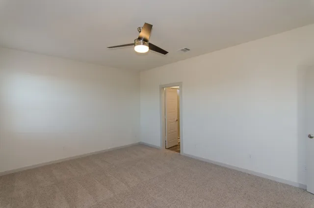 an empty room with a chandelier fan and windows