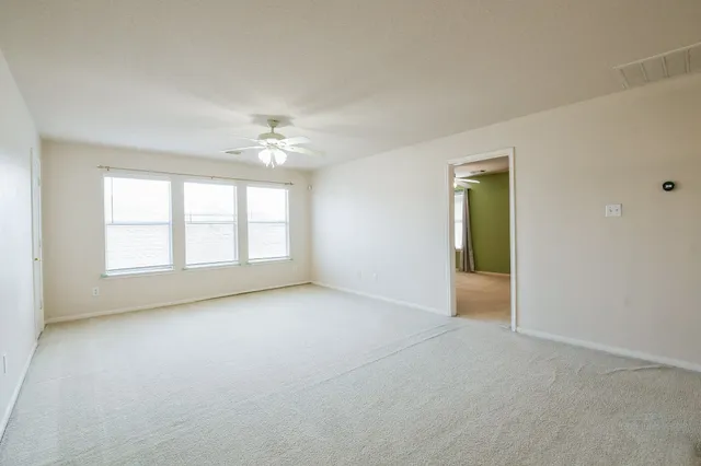 an empty room with windows and a ceiling fan