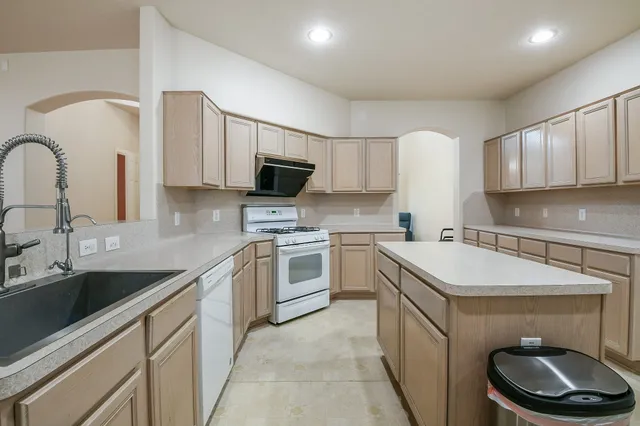a kitchen with kitchen island granite countertop a sink stainless steel appliances and cabinets
