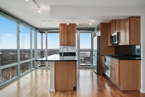 a large kitchen with kitchen island a large window a sink and stainless steel appliances