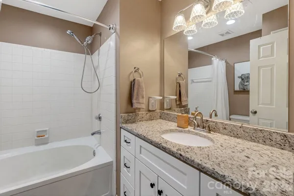 a bathroom with a granite countertop sink a mirror a vanity and a bathtub