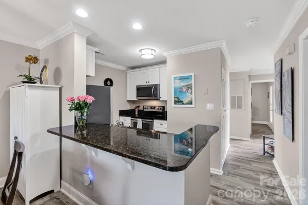 a kitchen with stainless steel appliances granite countertop a refrigerator a stove a sink a dining table and chairs