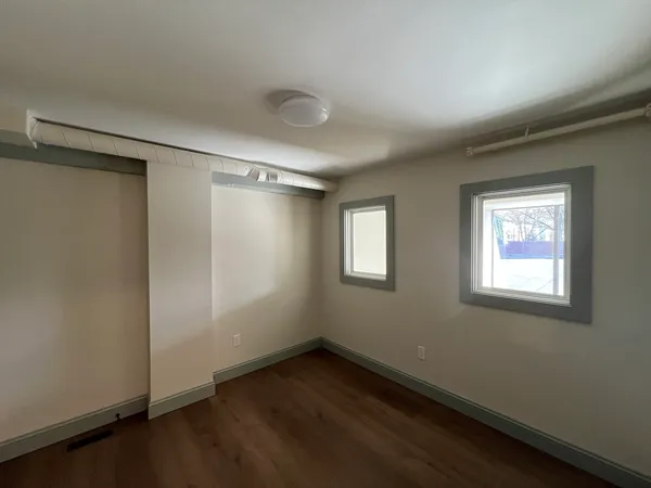an empty room with wooden floor and windows