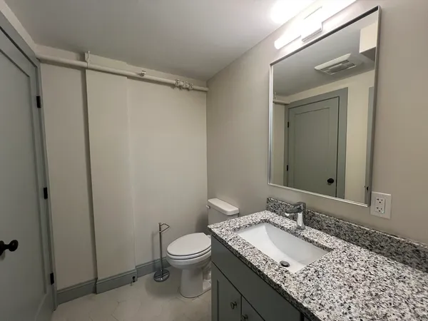 a bathroom with a granite countertop sink toilet and shower