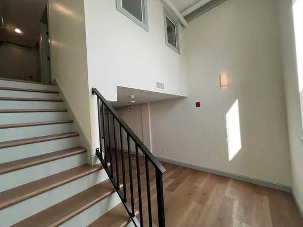 a view of staircase with lots of frames on wall and wooden floor