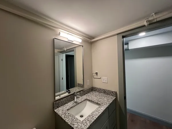 a bathroom with a granite countertop sink and a mirror
