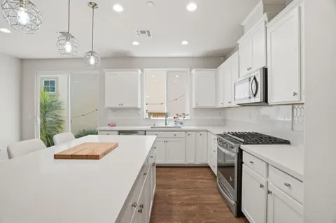 a large kitchen with kitchen island a sink and white cabinets