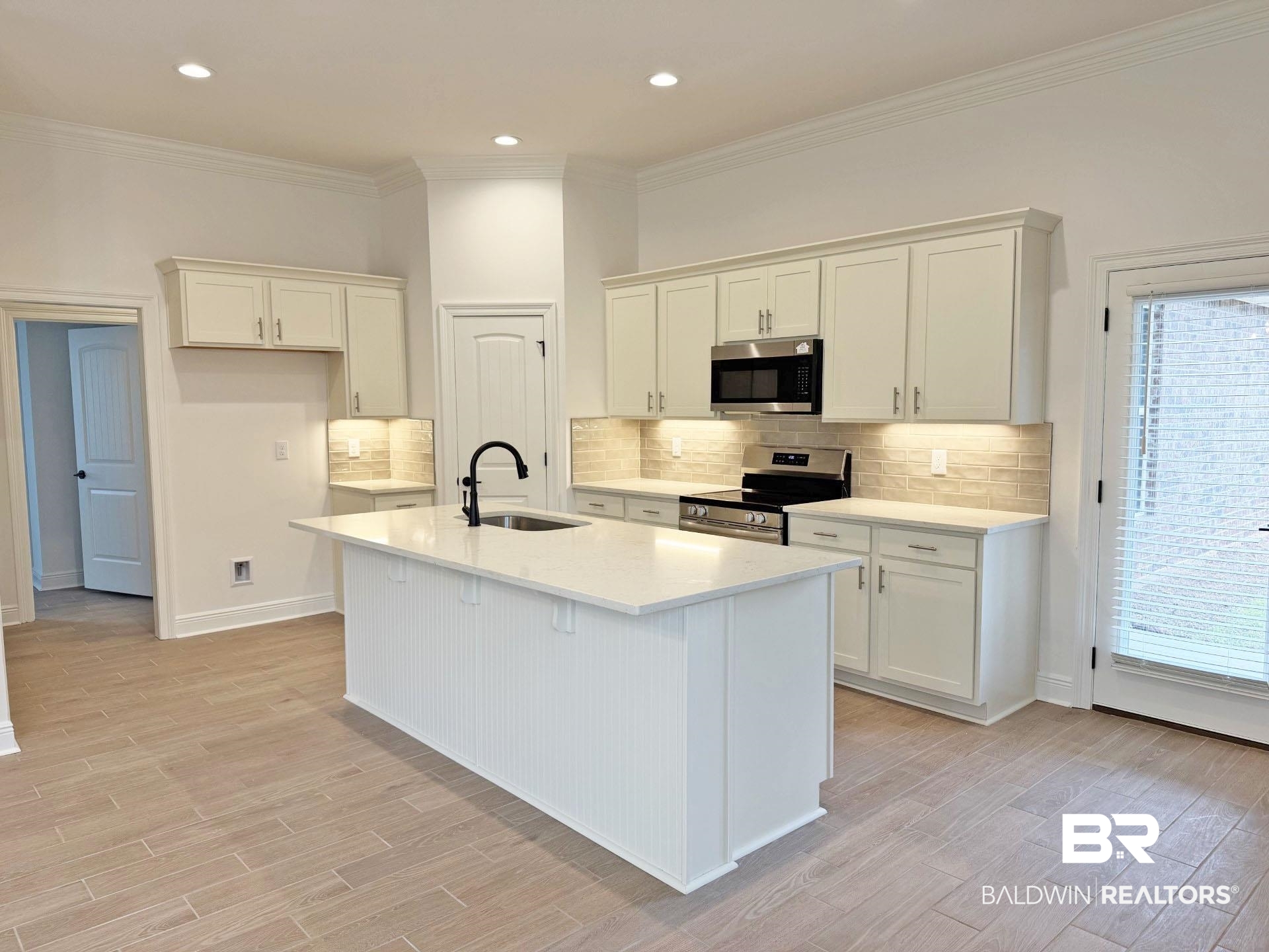1753 Breckinridge Place Foley, AL 36535 - Photo 4 of 24 Kitchen featuring a central island with a sink and matte black faucet, shaker-style cabinetry, stainless steel appliances, a tiled backsplash, and recessed lighting