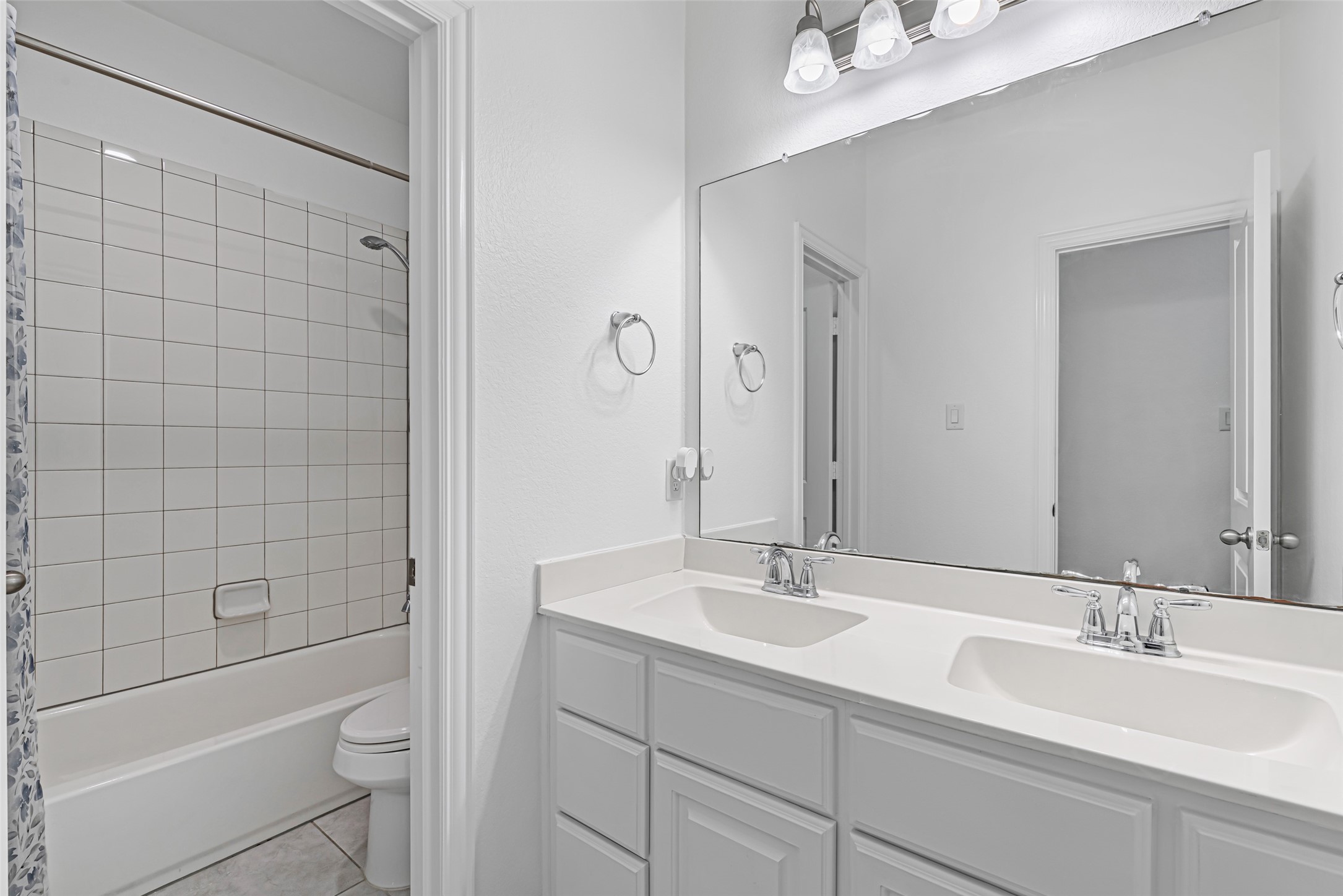 23635 Kingston Ridge Way Katy, TX 77493 - Photo 28 of 36 Upstairs shared bathroom featuring double sinks with modern fixtures, a large mirror, and a tiled bathtub/shower combination