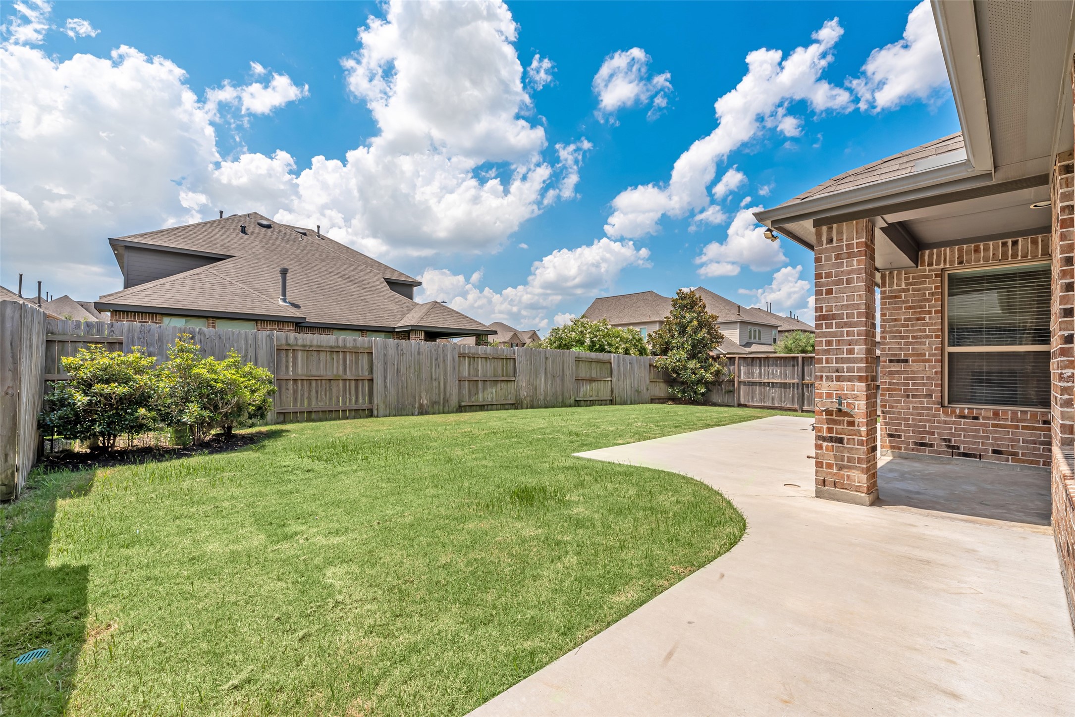 23635 Kingston Ridge Way Katy, TX 77493 - Photo 31 of 36 Spacious backyard with a well-maintained lawn and an extended patio area. It's enclosed by a wooden fence, providing privacy.