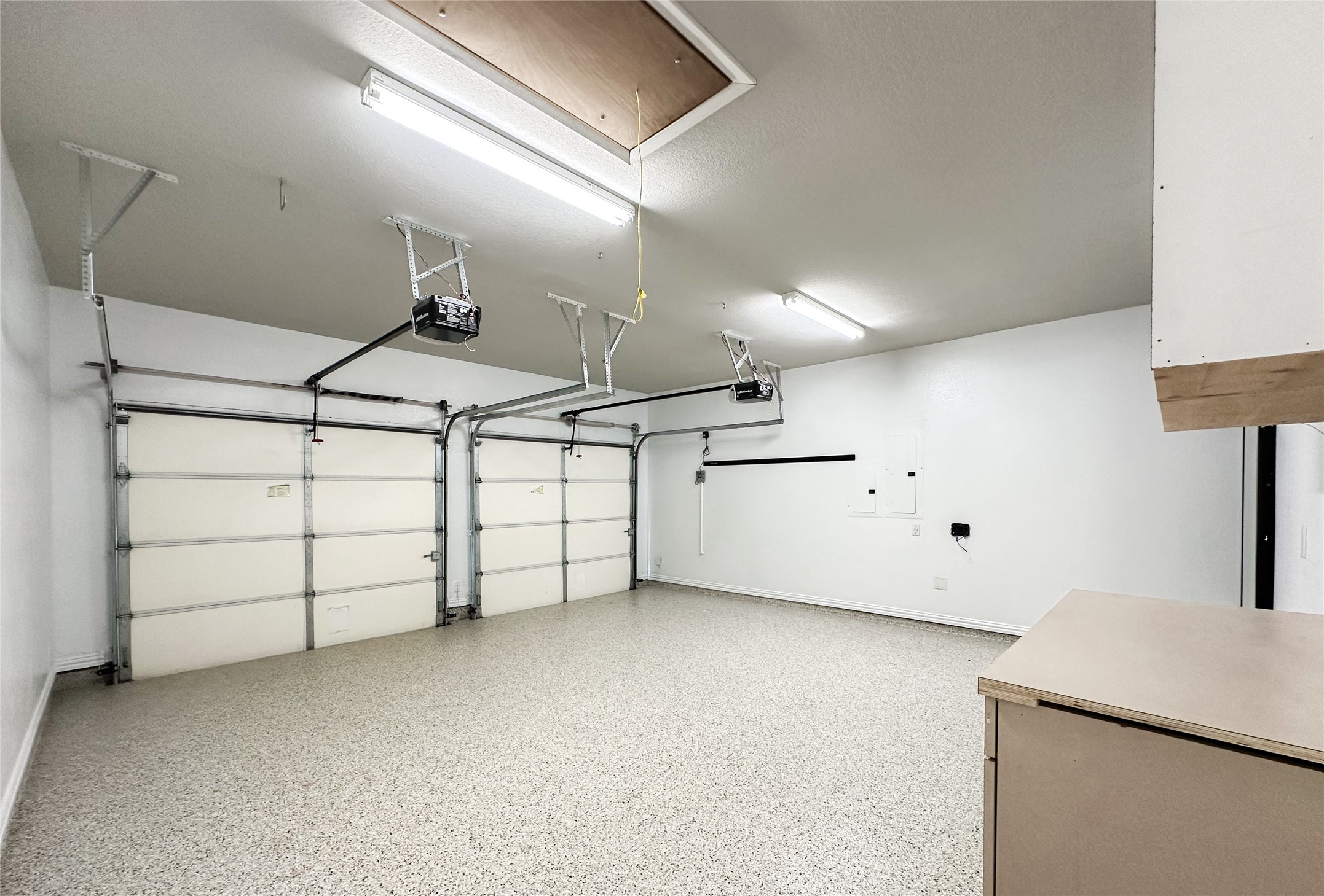 23635 Kingston Ridge Way Katy, TX 77493 - Photo 35 of 36 Clean two-car garage with epoxy flooring already installed, and ample overhead lighting. It includes two automatic garage doors and storage cabinets, offering functionality and convenience.