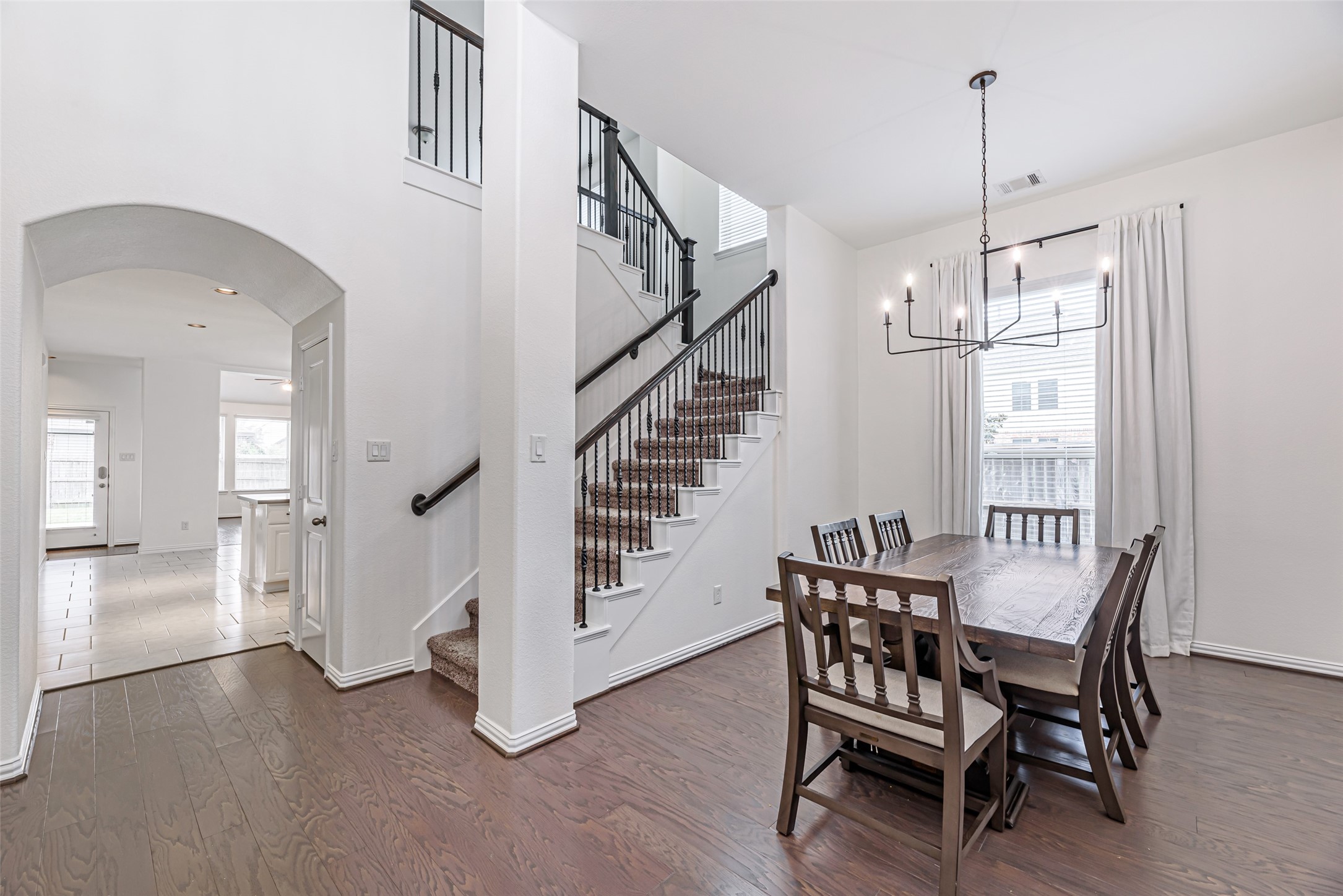 23635 Kingston Ridge Way Katy, TX 77493 - Photo 4 of 36 Upon entering you have a bright, modern dining area with hardwood flooring, & a stylish chandelier. The space is adjacent to a kitchen area, visible through an arched entryway, enhancing the open-concept feel.