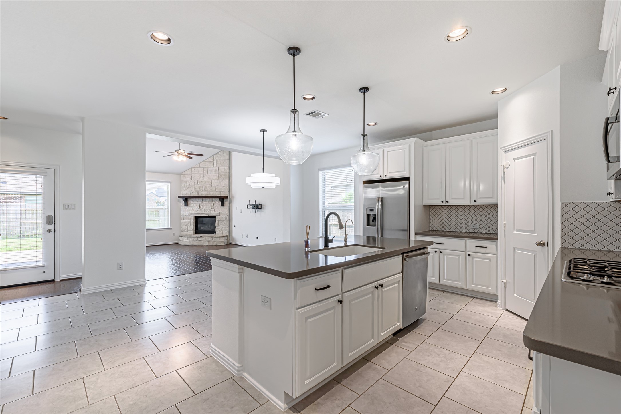 23635 Kingston Ridge Way Katy, TX 77493 - Photo 7 of 36 The kitchen opens into a spacious living area with a stone fireplace, offering a seamless flow for entertaining.