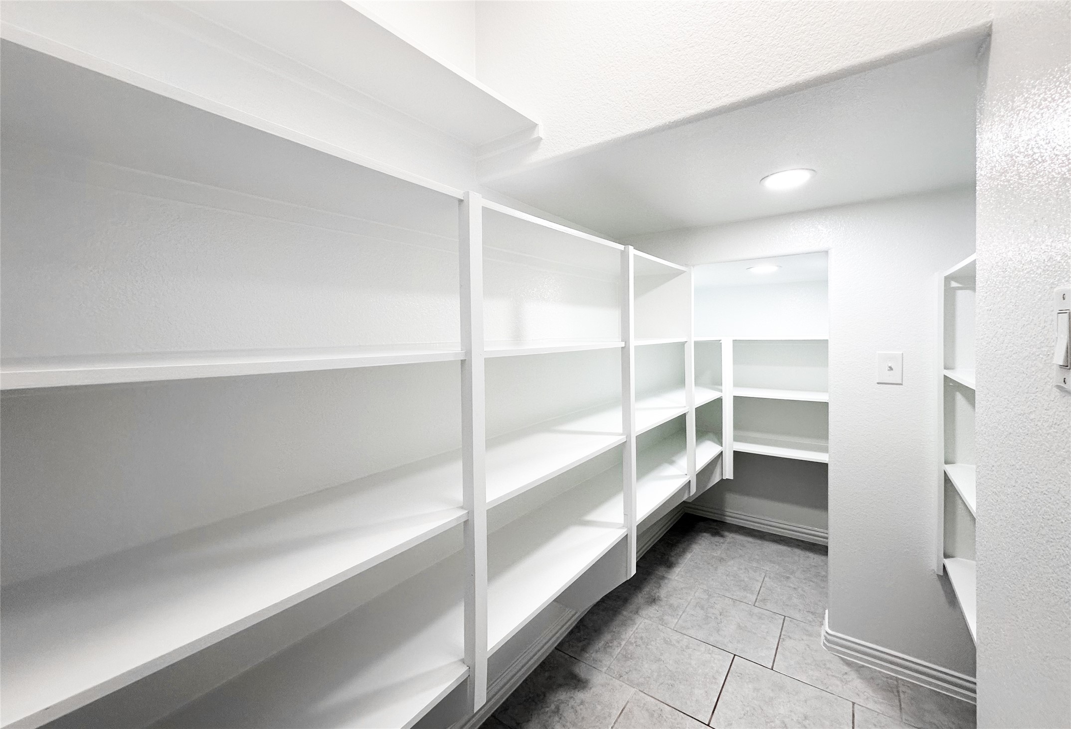 23635 Kingston Ridge Way Katy, TX 77493 - Photo 9 of 36 Very spacious walk-in pantry with ample shelving for storage, ideal for organizing kitchen essentials. The tiled floor adds a clean, modern touch.