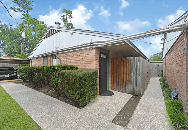 a view of a house with a small yard plants and large tree