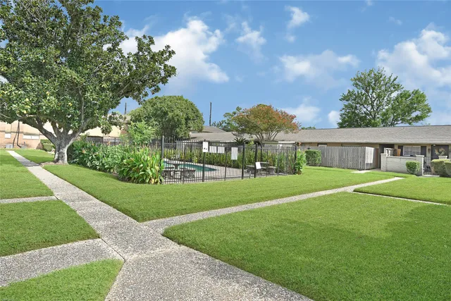 a view of a house with a big yard plants and large trees