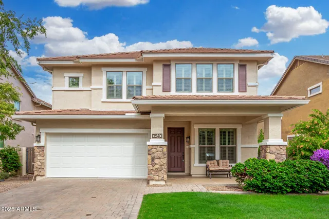 a view of a white house with a large windows and a yard with plants and large tree