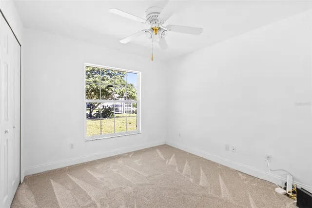 an empty room with a window and a fan