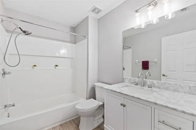a bathroom with a granite countertop sink a toilet and shower