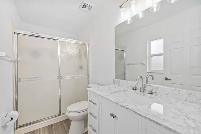 a bathroom with a granite countertop sink toilet and shower